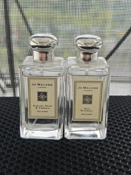 Comparaison visuelle entre un flacon de parfum de luxe de type Cologne et un dupe Jo Malone formulé en Eau de Parfum dans un flacon de laboratoire minimaliste.