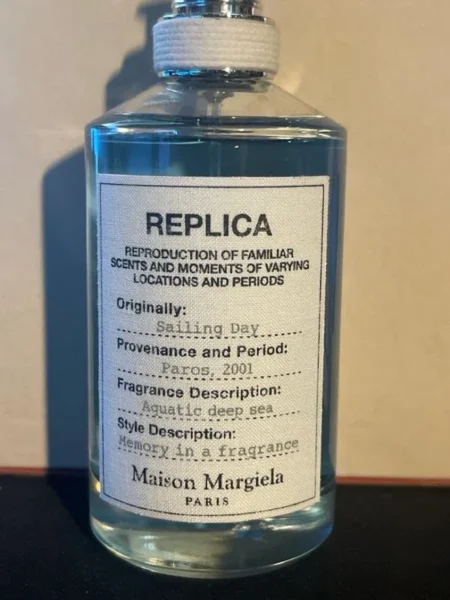 Comparatif visuel entre le flacon de luxe Maison Margiela Replica Sailing Day et une alternative dupe en concentration Eau de Parfum.