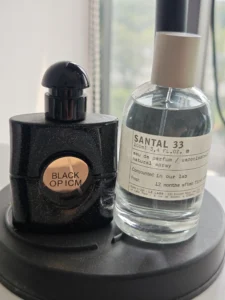 Comment choisir et porter un parfum santal boisé : Le guide ultime d'un expert pour une signature olfactive unique 2 Flacon de parfum santal boisé artisanal à côté d'une fragrance de créateur, illustrant l'importance de la macération et de la qualité des ingrédients.